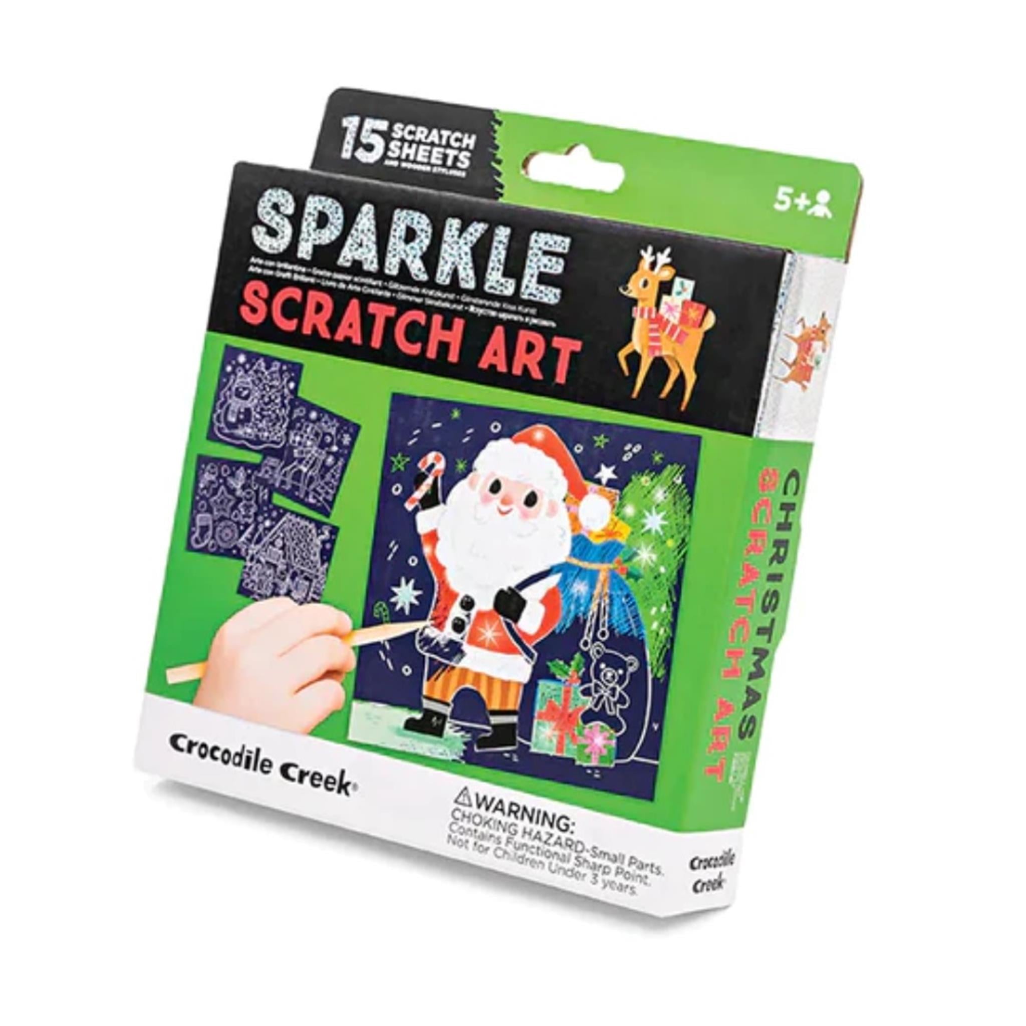 Packaging of Christmas Sparkle Scratch Art Kit by Crocodile Creek, featuring a child scratching a colorful Christmas themed scratch art sheet with a wooden stylus, and additional details about the product.