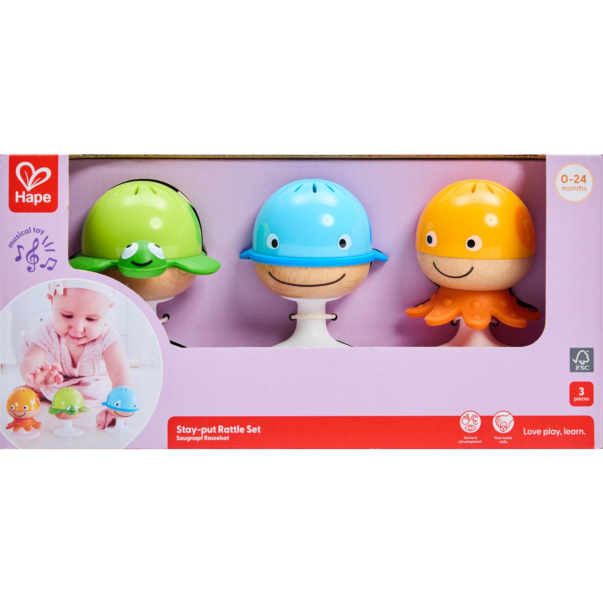 A packaged Stay Put Rattle Set by Hape, featuring three colorful rattle figures on stands, displayed in a purple open faced box.